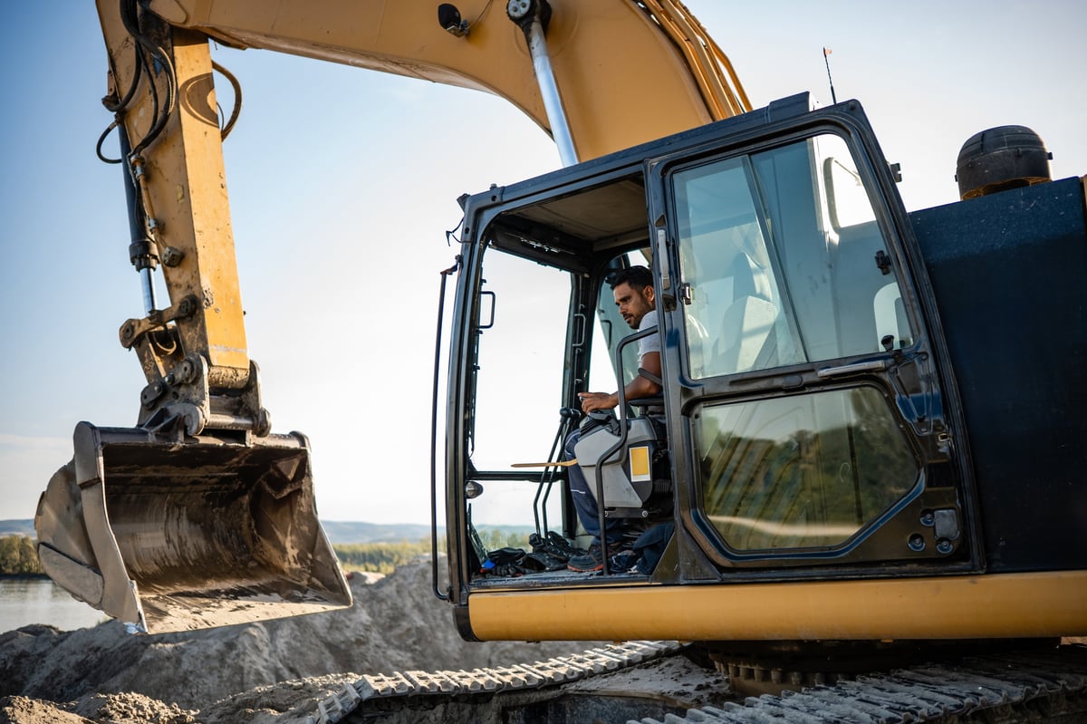 A construction worker operating a large excavator on an active job site, the kind of heavy equipment CBB Group helps businesses lease and finance