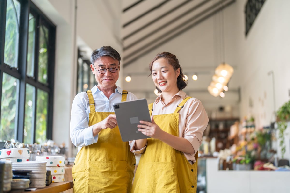 Two small business owners reviewing stock on a tablet in their retail shop, the kind of independent business CBB Group sources funding for