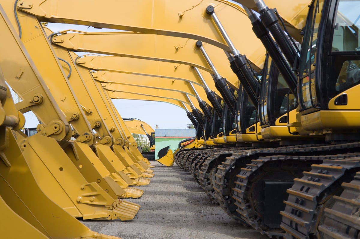 A row of excavators lined up on a working site